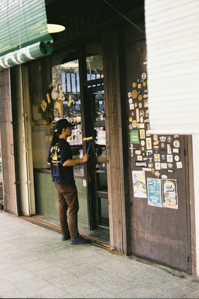 Technicien nettoyant les vitres d'une devanture commerciale avec une raclette