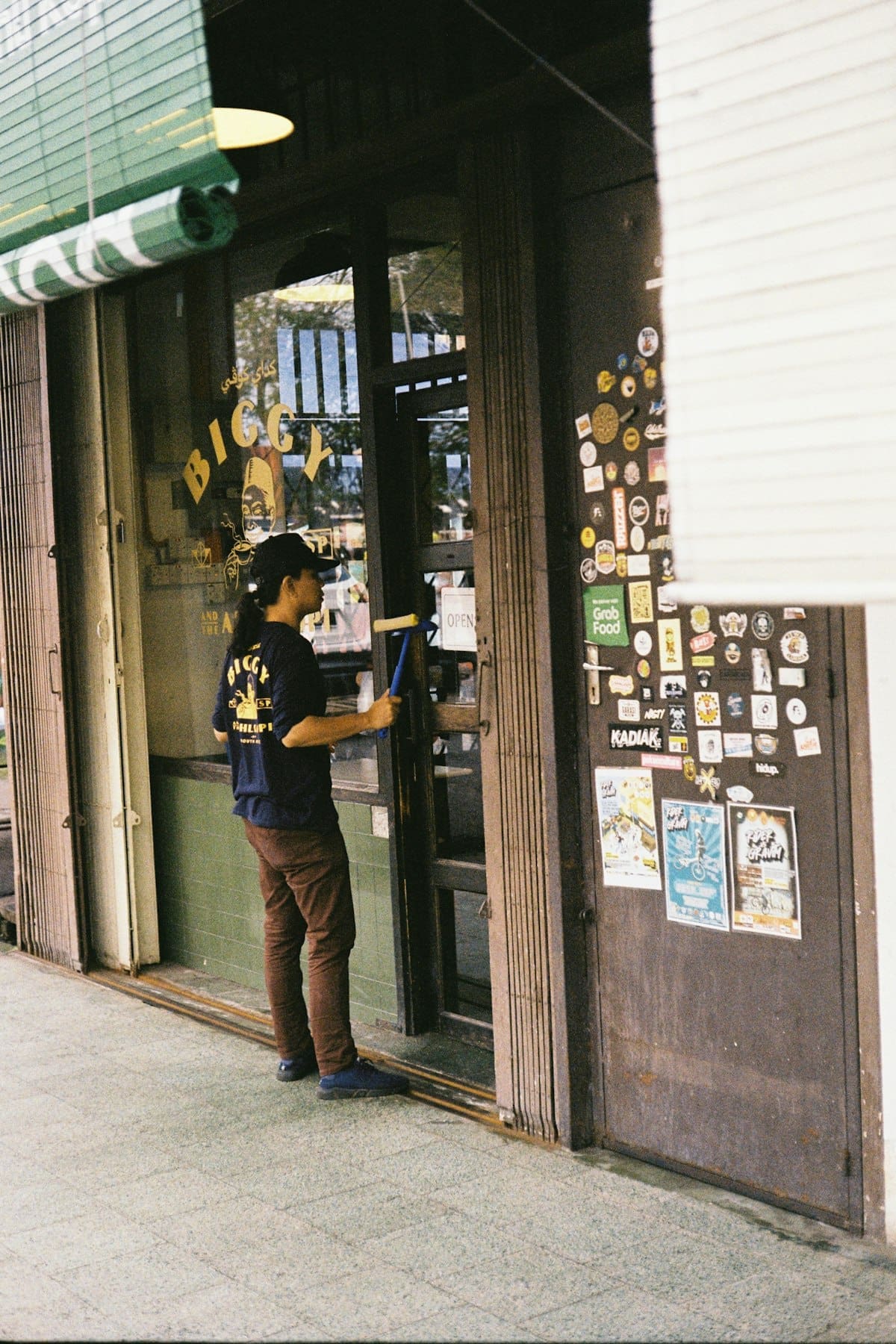 Technicien nettoyant les vitres d'une devanture commerciale avec une raclette